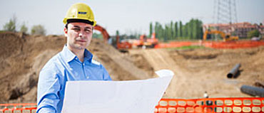 Guy holding a engineering drawing on a job site