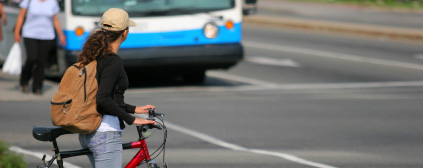 woman on bicycle crossing road in front of a stopped public transit bus